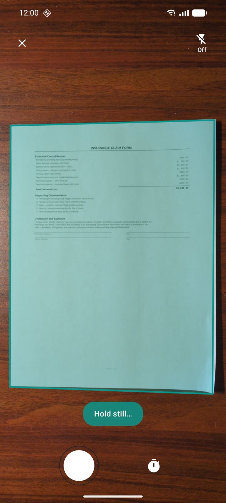DocuScanr camera view detecting the edges of a paper document on a wooden table, with a teal Hold still prompt at the bottom.